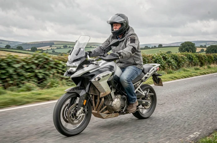 Homme de 60 ans en selle sur une moto d'aventure sur une route de campagne, illustrant la reprise de la moto à la retraite